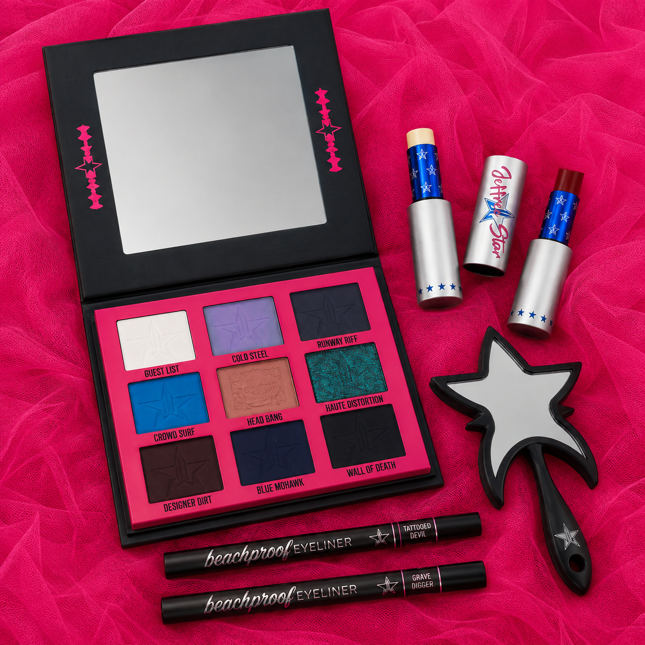 Colección Heavy Metal Couture de Jeffree Star con paleta de sombras, espejo de mano, dos bálsamos labiales y delineadores Beachproof sobre tul rosa intenso.